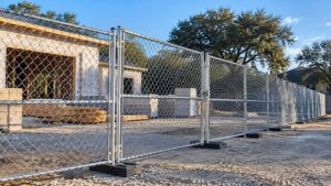 Temporary chain-link fence panels with weighted bases surrounding a construction site.